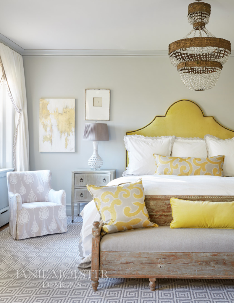 bedroom with yellow headboard and chandelier over bed