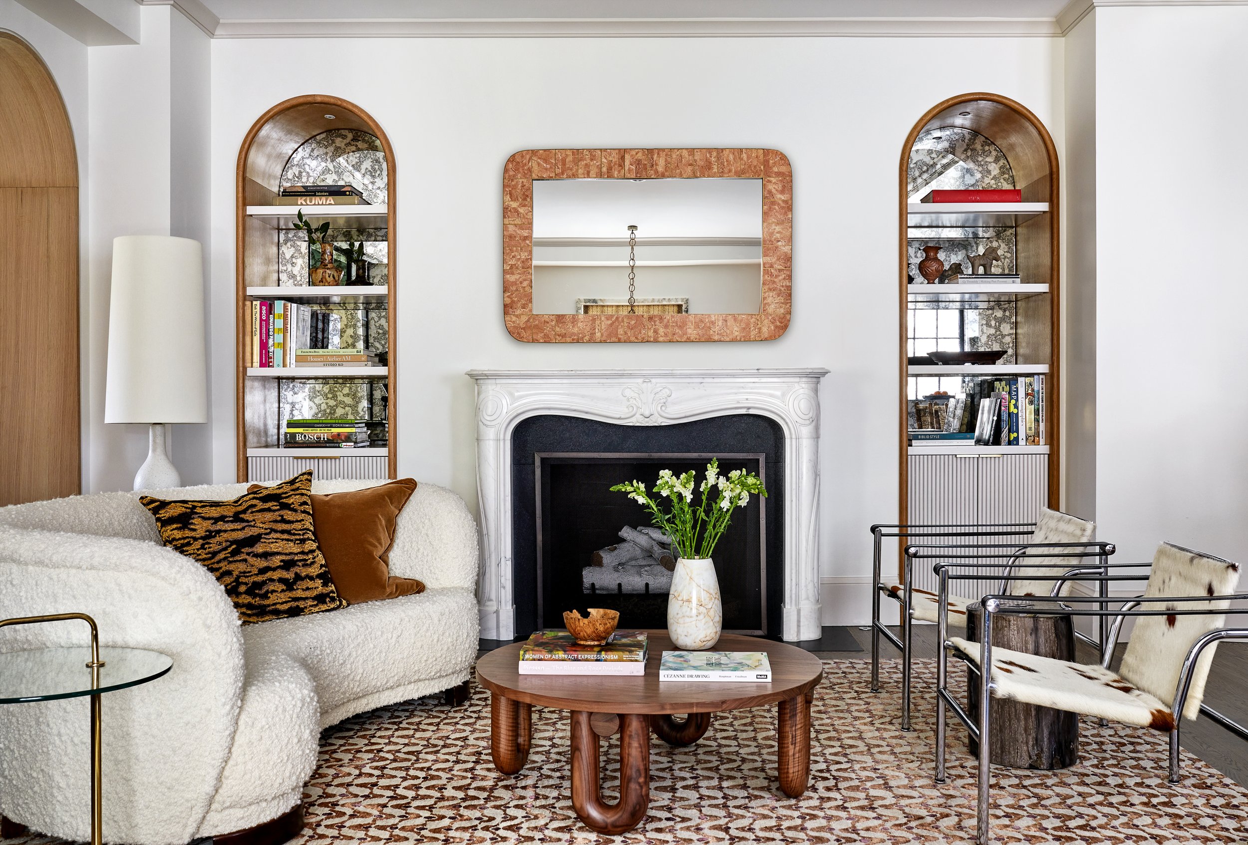 Neutral living room with sophisticated decor - curved sofa with a round coffee table and arched bookcases -Zoe Feldman | Stacy Zarin Goldberg Photography