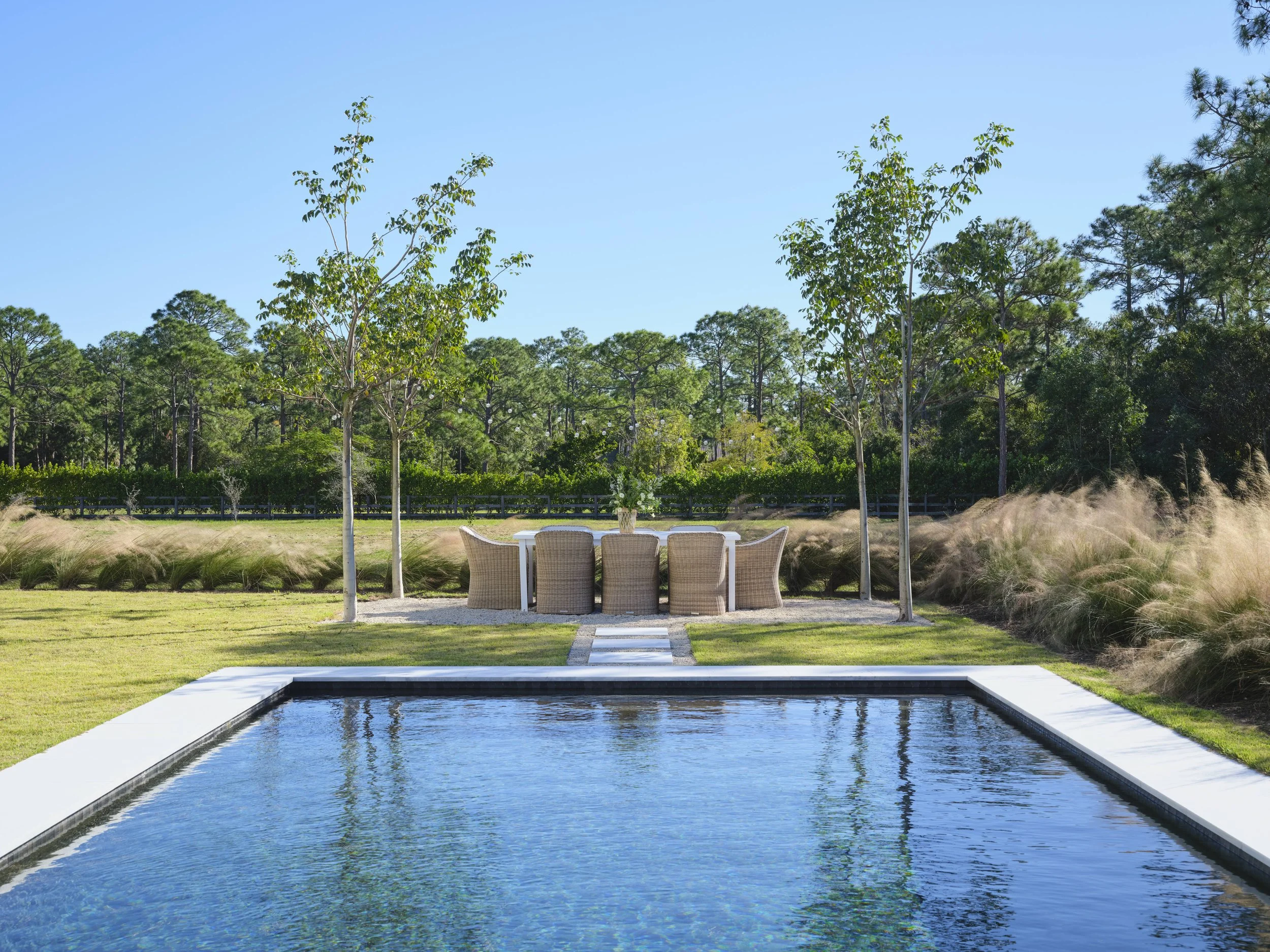You know how much we love the designs of Kara Miller. Her new home is a wonderful getaway — even if the getaway is only on your monitor! Brantley Photography pool with dining area with wicker chairs