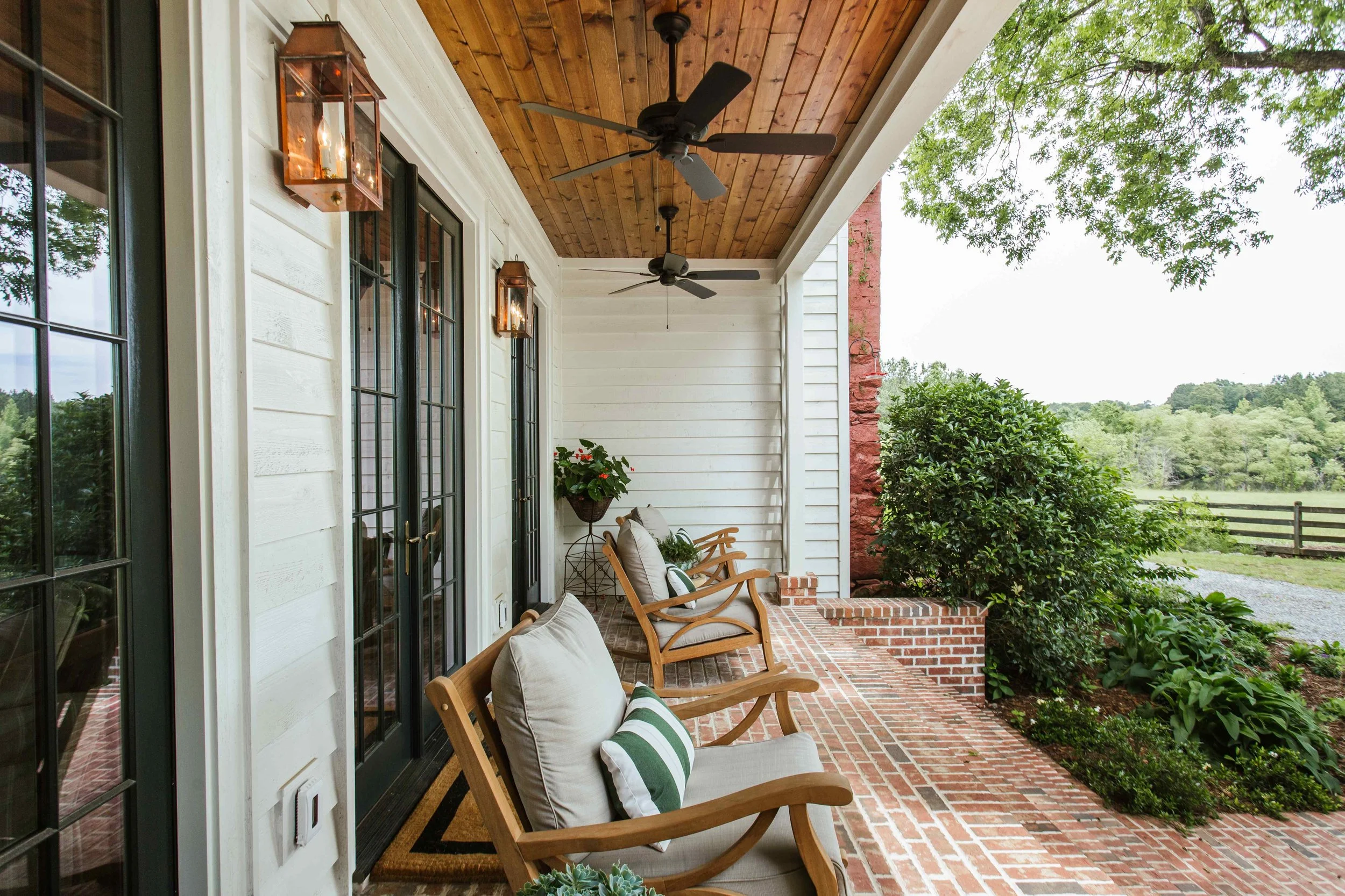 Perfectly proportioned, wholly welcoming and full of Southern charm, this beautiful farmhouse designed by The Misfit House and photographed by the amazing Kristin Karch Photography  is totally making our day.  Take a peek, and we think you’ll understand why! Love the covered porch with ceiling fans and copper lanterns