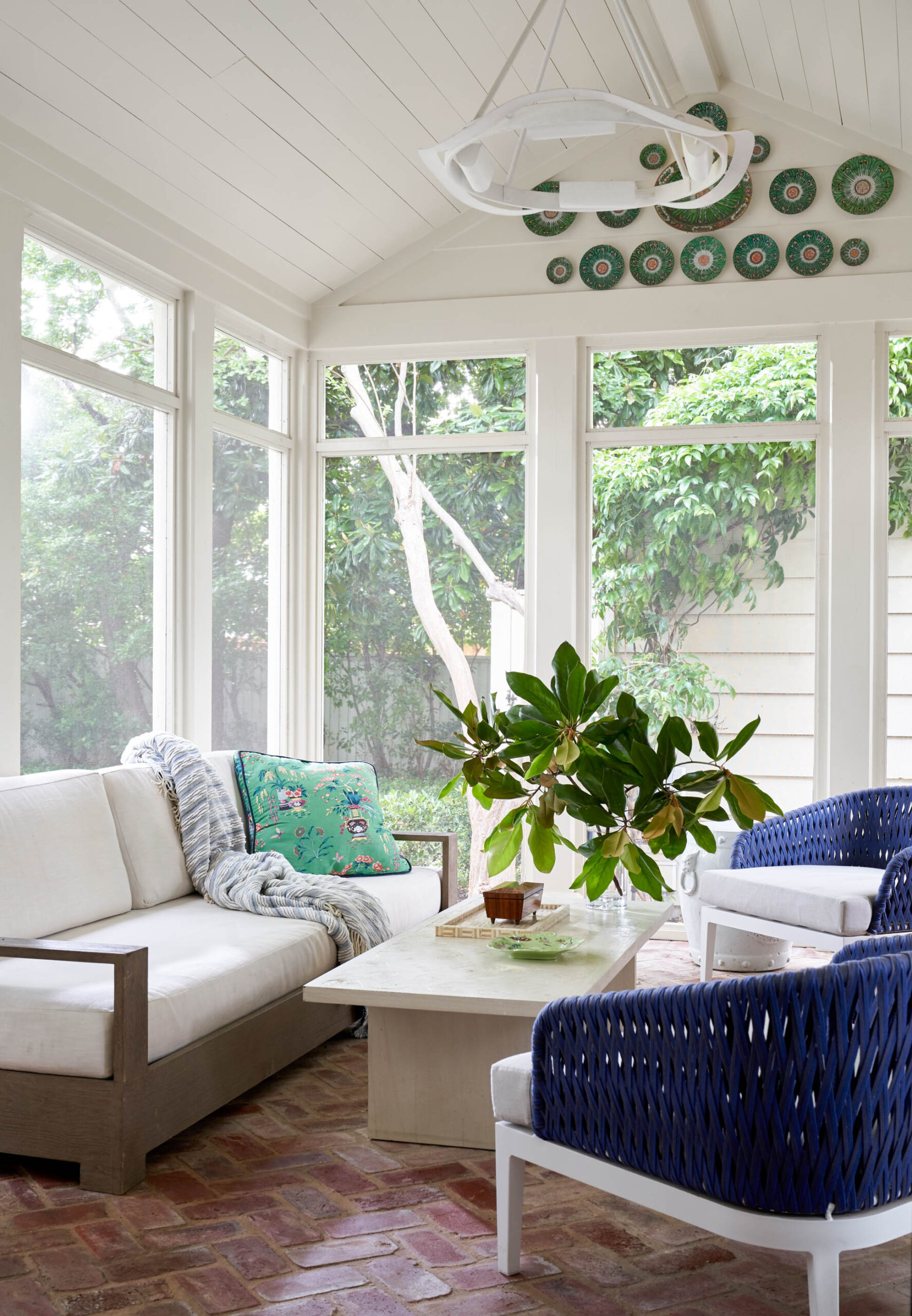 coffee table decor - screened porch with beautiful light fixture and blue wicker chairs