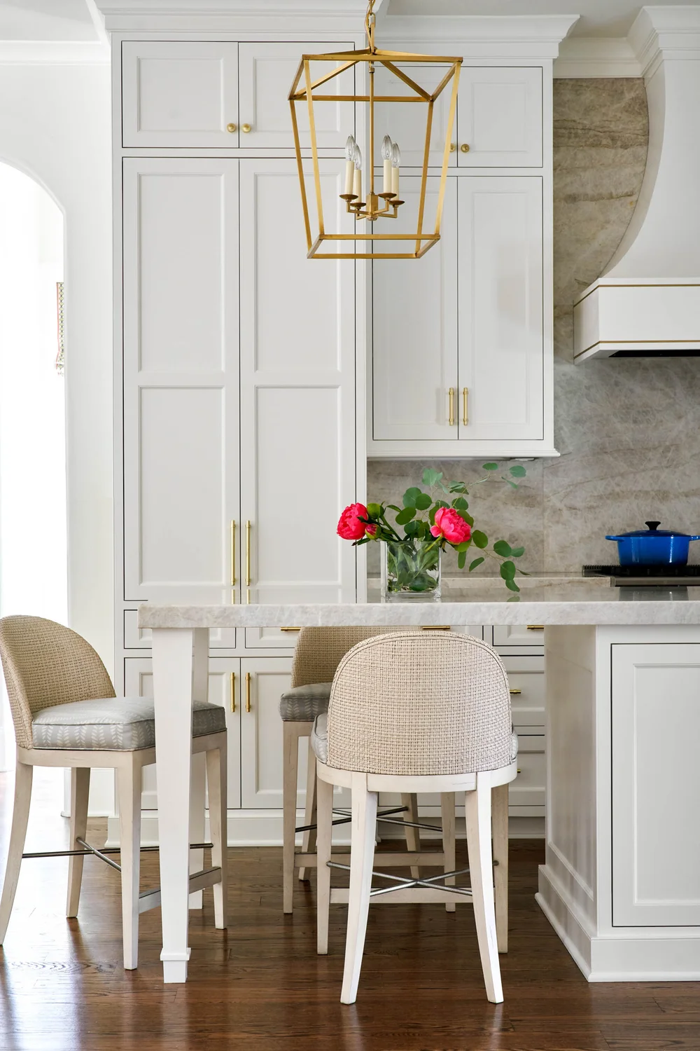 Neutral doesn’t have to mean boring, as evidenced by this kitchen. With the warm greige cabinetry, richly veined stone, and a pop of color with flowers and cookware, it’s livable, versatile and perfect for entertaining. - Nathan Schroder PHotography