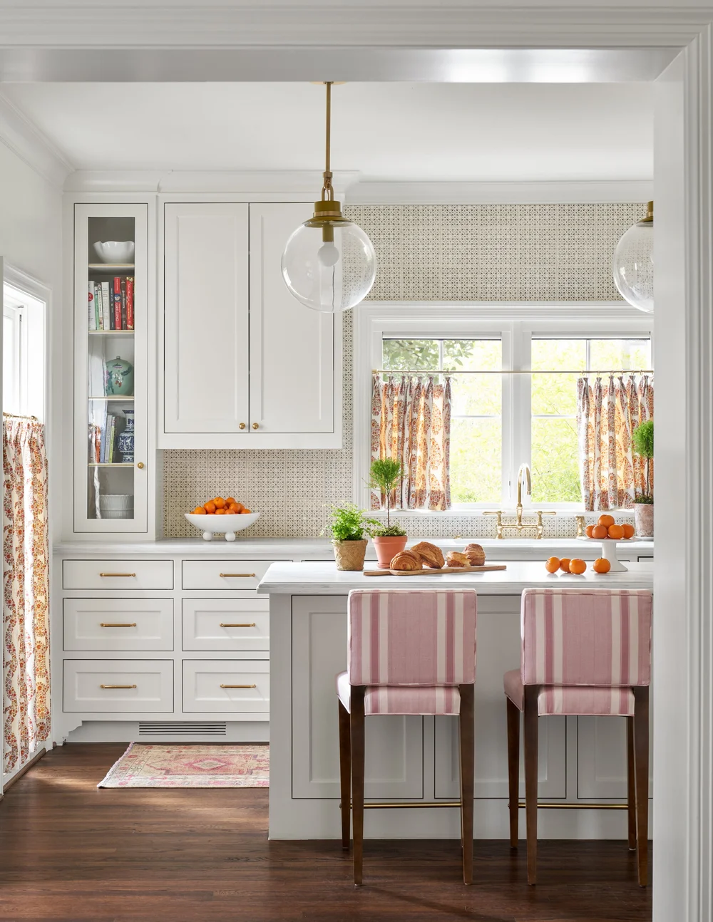At first glance, this kitchen feels classic, but with a closer look, and you’ll notice the unexpected details that Jenkins interiors is brilliant at using—an interesting backsplash, sculptural lighting, and fun fabrics—that keep it fresh - white countertops and white cabinets