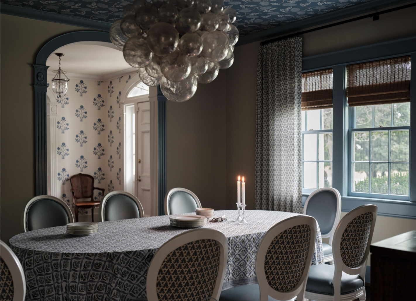 There was a time when open floor plans felt like the ultimate luxury. But lately, we have noticed a shift to rooms with a purpose. Love a library with Visual Comfort brass library lights and beautiful moody blue walls - Sabbe Interior design | Joseph Bradshaw Photography - Beautiful dining room with oval table and Jennifer Neill Talia chandelier