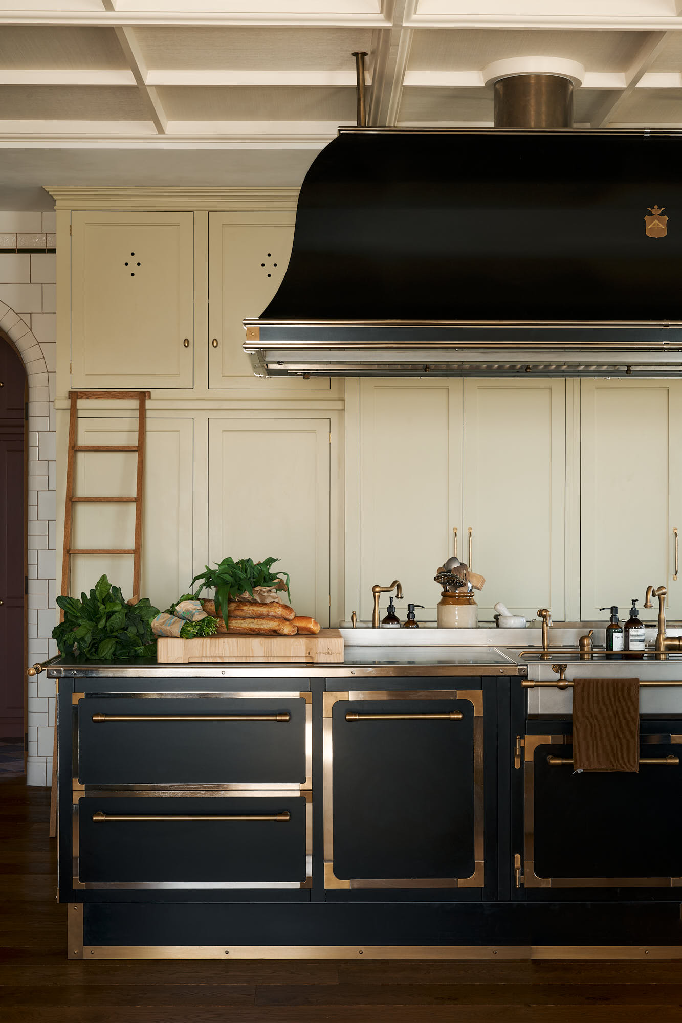 You know when you walk into a kitchen that just has a certain feel of refinement and style, but you can't quite figure out why. On Design Chic, we have featured hundreds of kitchens, and each one has subtle details that combine to form a spectacular whole - ones that separate a standard kitchen from one that feels elevated. Here are the 6 elements that create a stunning custom kitchen design- deVOLKitchens | Officine Gullo Range | Tim Cooper Photography - black range and black range hood with tan cabinets and library ladder