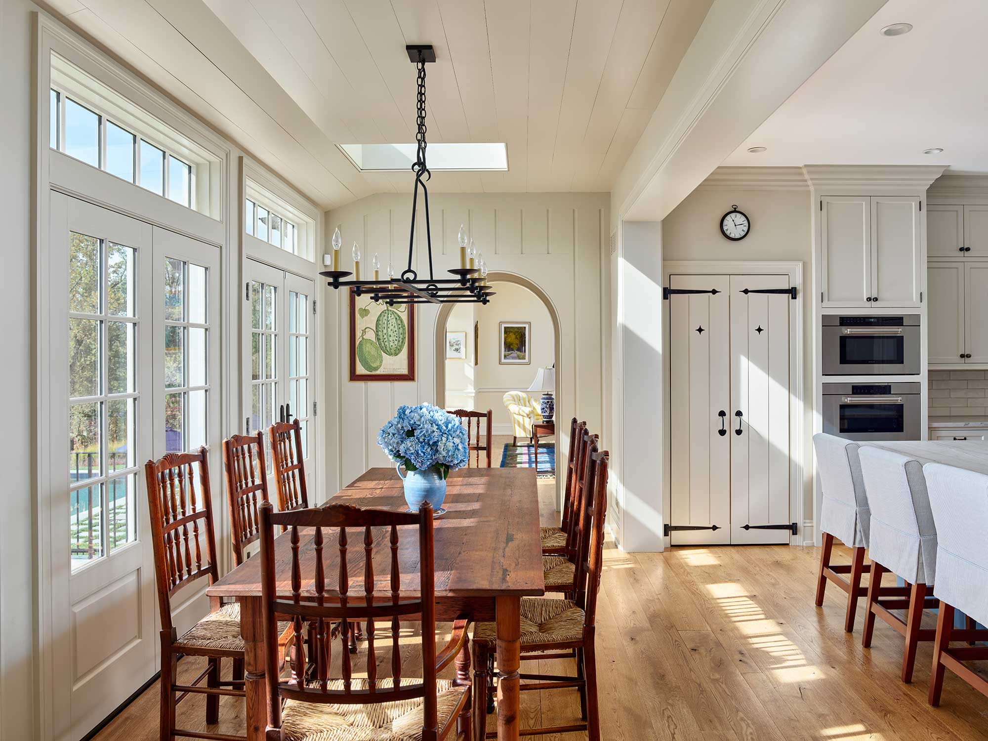 We’d say this home, designed by Archer & Buchanan Architects, hits all the high notes of style. Builder: Cushing Custom Homes, Inc. Beautiful farmhouse kitchen in white with black iron pulls and knobs - rectangle dining table