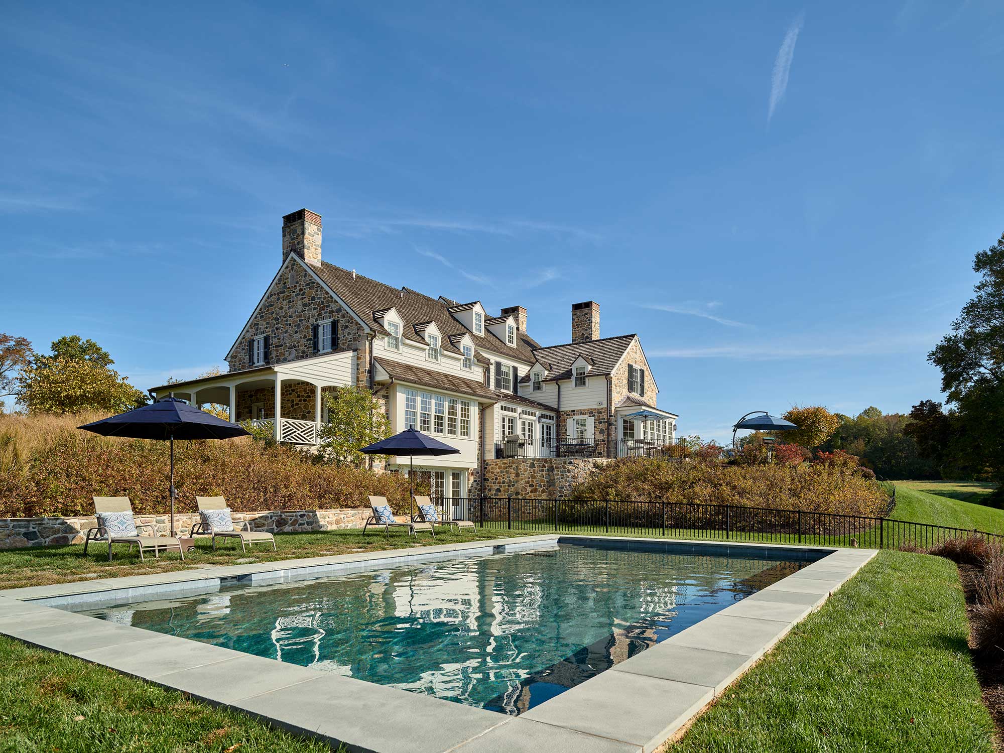We’d say this beautiful stone farmhouse, designed by Archer & Buchanan Architects, hits all the high notes of style. Builder: Cushing Custom Homes, Inc. Beautiful pool and landscaping in this farmhouse