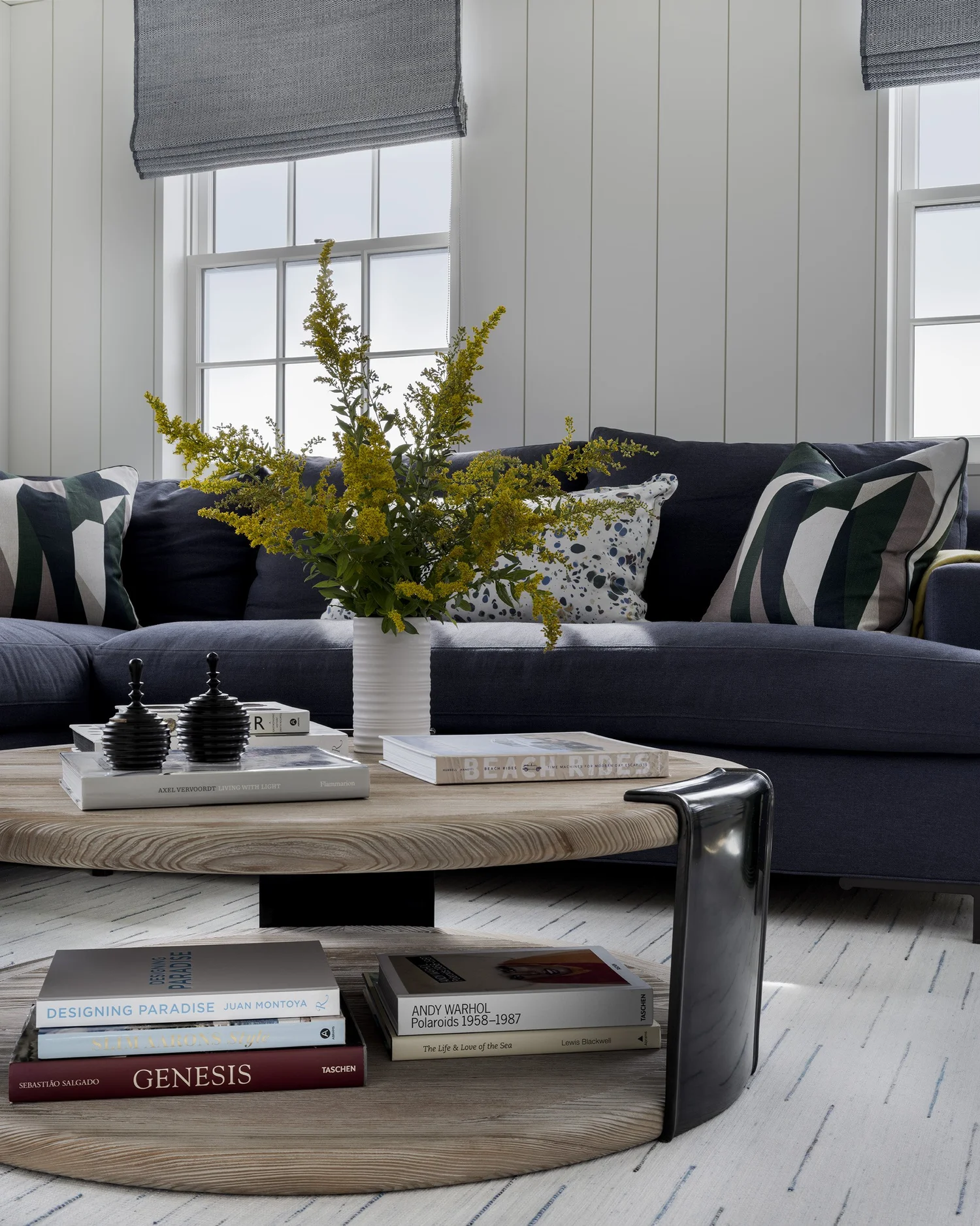 Tour a stunning home designed by the talented Honey Collins Interiors and beautifully photographed by Alison Gootee Photography.  Neutral enough to be calm, textured enough to be interesting, and layered into complete coziness, this is the perfect home for friends and family.  Whatever your design goals, you’ll find the inspiration to get your home makeover started on the right foot! Navy blue sectional sofa with white paneled walls in living room