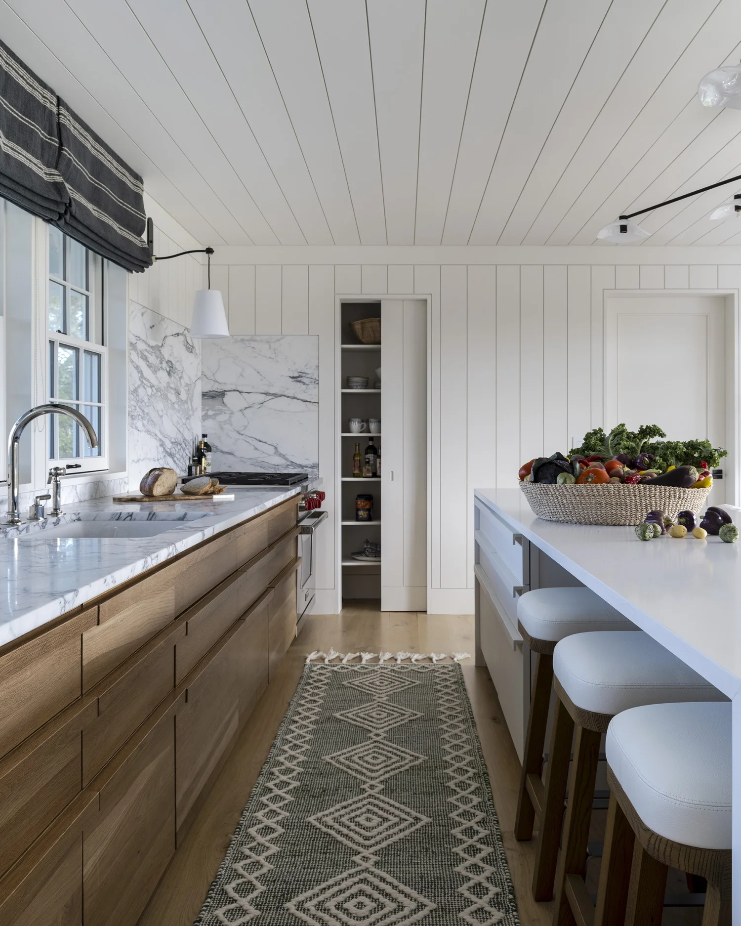We hope you are having a great week–and are in the mood for touring a stunning Nantucket coastal home designed by the talented Honey Collins Interiors and beautifully photographed by Alison Gootee Photography.  Neutral enough to be calm, textured enough to be interesting, and layered into complete coziness, this is the perfect home for friends and family.  Whatever your design goals, you’ll find the inspiration to get your home makeover started on the right foot! Happy Thursday! white kitchen and stained wood cabinets with marble countertops and backsplash