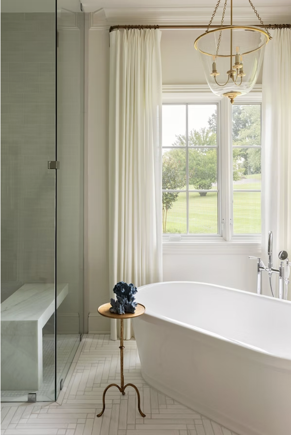Interiors with just the right amount of personality are hallmarks of this talented designer’s style. Take a break, take a peek, and let us know which space of Cerminara Designs is your favorite! chic white bathroom with gorgeous glass and brass bell jar lantern over the freestanding tub -Photo: @carolinesharpnack