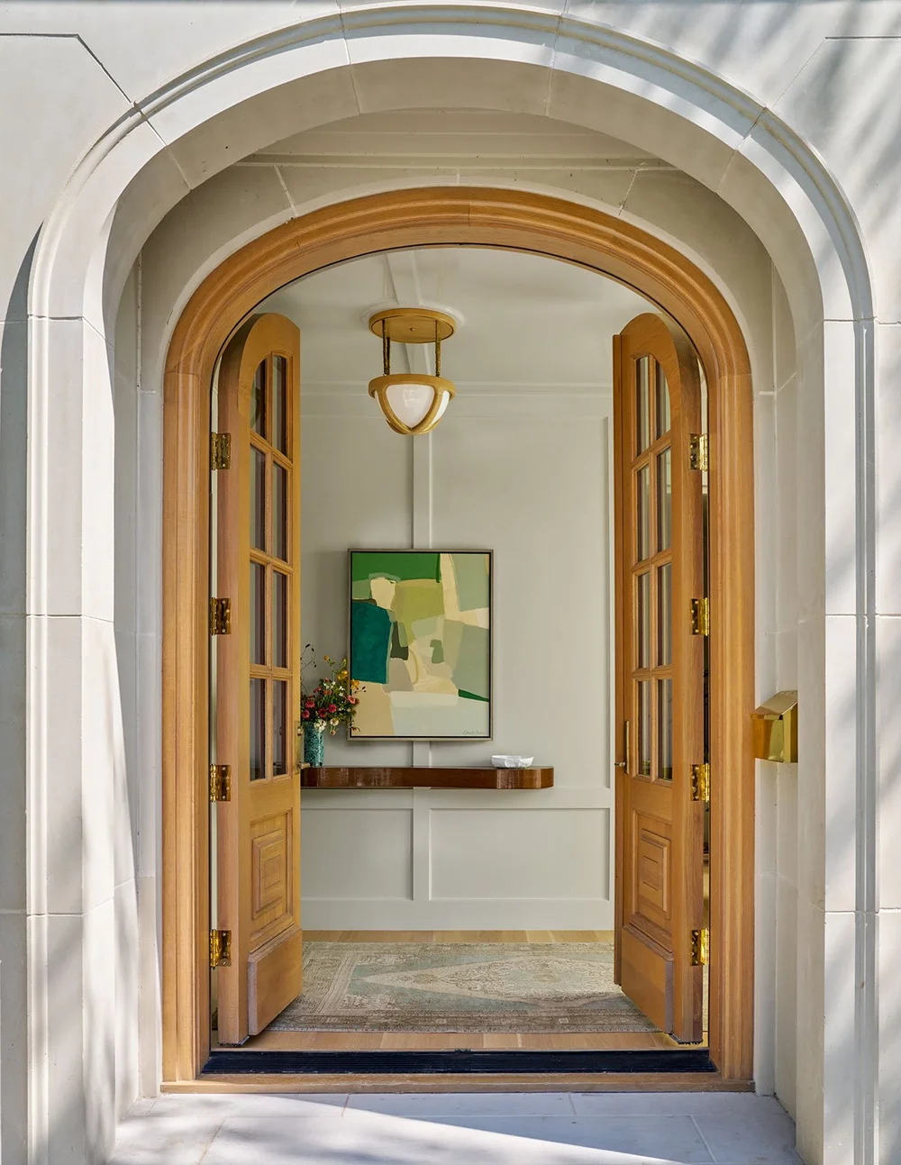 In a world full of minimalism and clean lines, traditional design is making a quiet comeback. It’s the perfect mix of classic touches and updated details, well-suited for family living and entertaining. Where stunning moldings and architectural details live comfortably with more casual room. Mary Beth Wagner Interior Design - Nathan Schroder Photography - Love the arched doorway in this foyer with modern art and applied molding