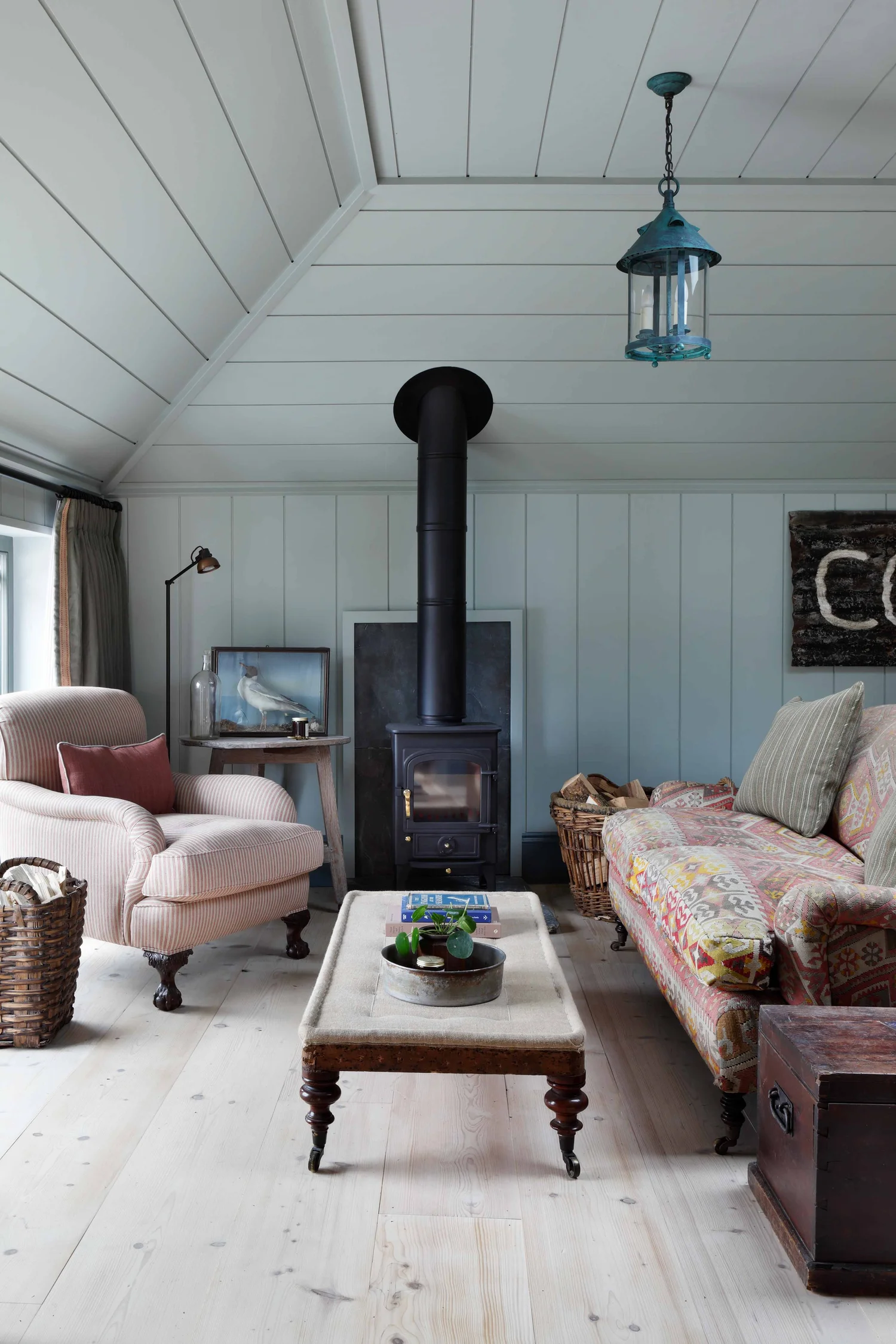 This former fisherman's house, imagined as a sea captain's home, is totally unique, quietly luxurious, and unforgettably chic. Ham Interiors - Alexander James Photography - charming British design with shiplap in living room and vintage fabrics and old fireplace