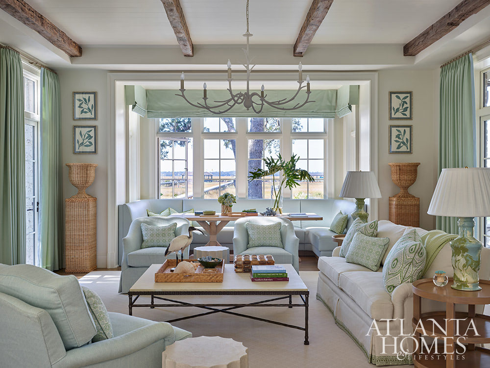 Heather Dewberry, one of our favorite designers,  Architect Josh Youngner,  Builder Matthew McHale, Ramsey McHale, and Landscape Architect Sea Island Landscape, and Stylist Jimmie Henslee in this months Atlanta Home & Lifestyle, make designing a coastal oasis look effortless, as evidenced by this gorgeous Sea Island Home. Beautiful living room with the wood beams in light blue and white and a water view.  Love the wicker colums and plant stands