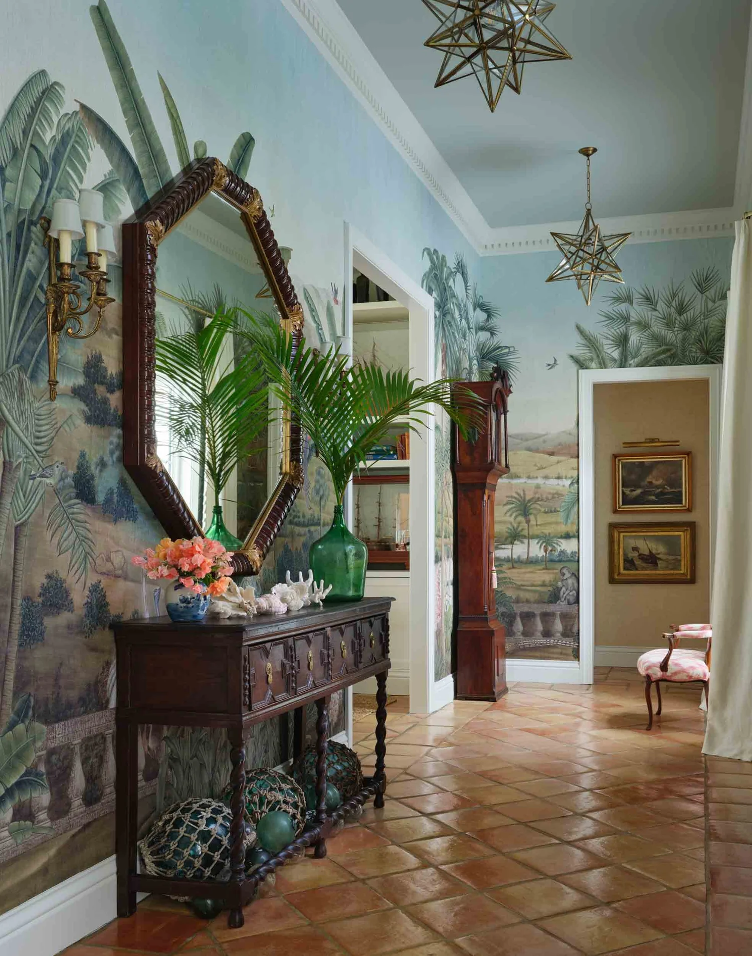 Tour a traditional coastal home with beautiful antiques, collected charm, and a relaxed seaside feel. You'll love every fabulous detail! Beautiful deGourney wallpaper in the foyer with palm trees and antique console table, and terra cotta tiles