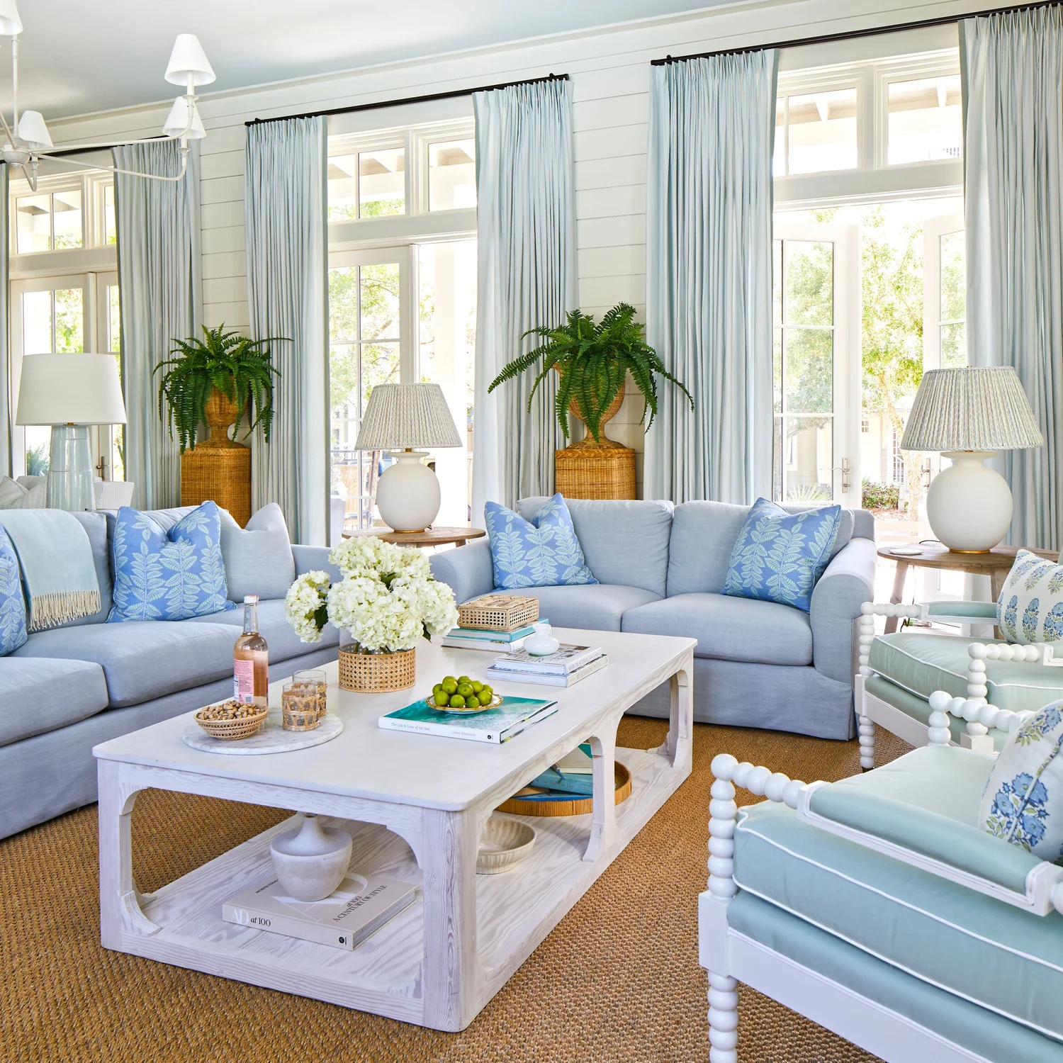 Sometimes a blue and white palette can feel predictable, but in this utterly charming Kara Miller-designed beach house, photographed by , Laurey W. Glenn and styled by Lindsey Ellis Beatty, it feels fresh and inviting. The various color tones, natural materials, and textured accents ground each space, creating a livable home with plenty of style. Blue and white beach house with wicker planters and large transom windows
