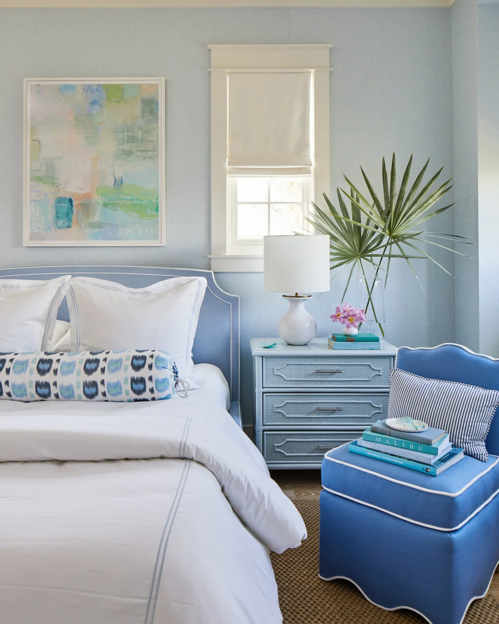 Utterly charming Kara Miller-designed beach house, photographed by , Laurey W. Glenn and styled by Lindsey Ellis Beatty, feels fresh and inviting. The various color tones, natural materials, and textured accents ground each space, creating a livable home with plenty of style. bedroom with a long neck roll pillow and abstract art