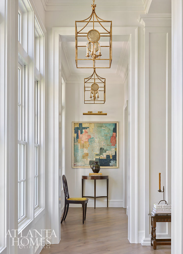 INTERIOR DESIGN: Kim Scodro Interiors| ARCHITECT: William Court, Court Atkins Group | BUILDER: Brett Flanagan, Flanagan Development | LANDSCAPE ARCHITECT: Troy Anderson, Spartina Studio | CABINETRY DESIGN: Jamestown Designer Kitchens | PHOTOGRAPHY: Emily Followill Photography | STYLIST: Eleanor RoperBeautiful hallway with barss chandeliers and abstract art