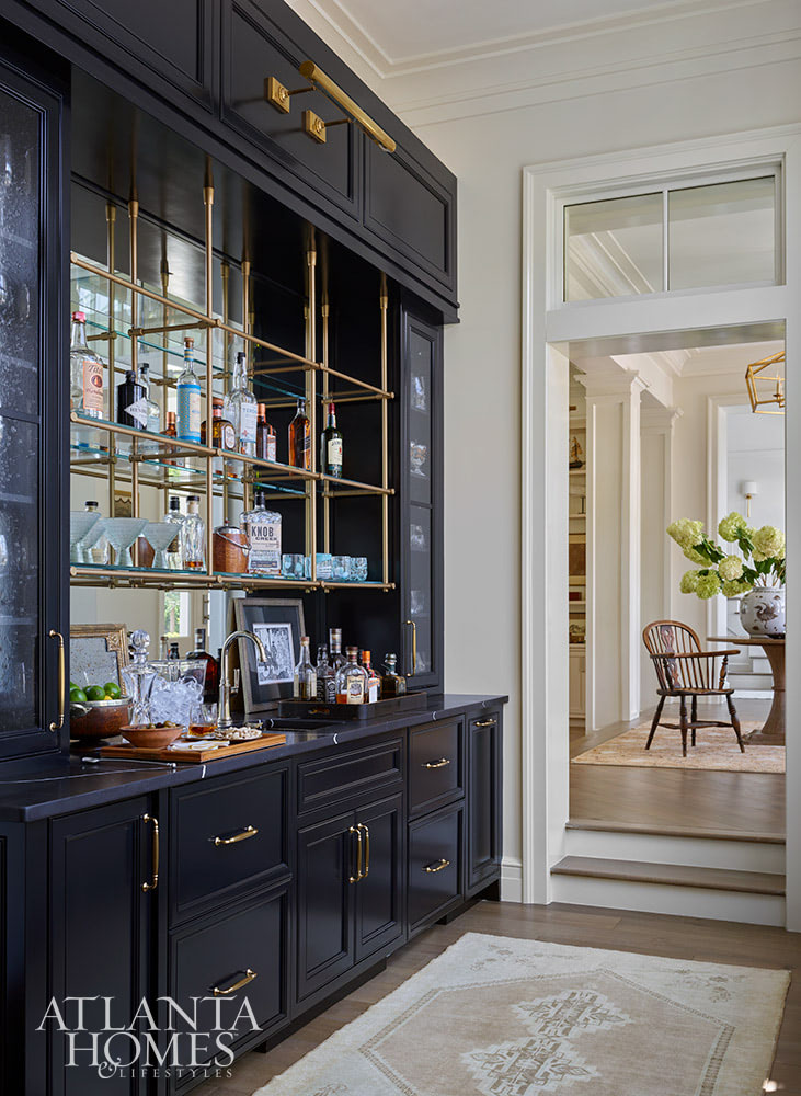 INTERIOR DESIGN: Kim Scodro Interiors| ARCHITECT: William Court, Court Atkins Group | BUILDER: Brett Flanagan, Flanagan Development | LANDSCAPE ARCHITECT: Troy Anderson, Spartina Studio | CABINETRY DESIGN: Jamestown Designer Kitchens | PHOTOGRAPHY: Emily Followill Photography | STYLIST: Eleanor Roper With the days getting longer and the warmer, it's the perfect time to take a trip to a gorgeous St. Simons Island home . Lush surroundings and even lusher interiors make this the ideal getaway. Butler's pantry in dark blue with brass library lights and brass hangin shelf