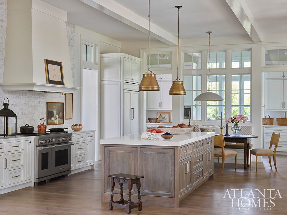 INTERIOR DESIGN: Kim Scodro Interiors| ARCHITECT: William Court, Court Atkins Group | BUILDER: Brett Flanagan, Flanagan Development | LANDSCAPE ARCHITECT: Troy Anderson, Spartina Studio | CABINETRY DESIGN: Jamestown Designer Kitchens | PHOTOGRAPHY: Emily Followill Photography | STYLIST: Eleanor Roper With the days getting longer and the warmer, it's the perfect time to take a trip to a gorgeous St. Simons Island home . Lush surroundings and even lusher interiors make this the ideal getaway. Kitchen with stained island but white cabinets and brass pendants over island