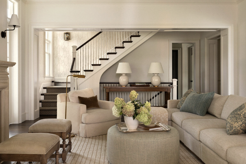 one-of-a-kind place in Lake Washington, designed by the talented Marianne Simon Interior Design, beautifully photographed by Aimee Mazzenga, and styled by Cate Ragan Stylist. Neutral living room with 2 stools in front of the fireplace and a round ottoman