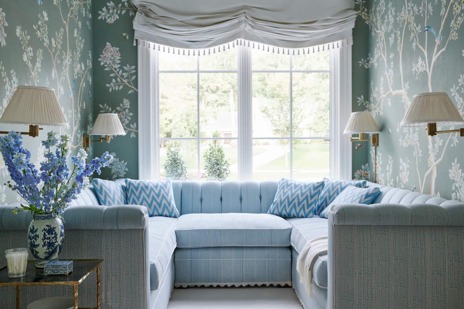 Blue and white living room with tufted sectional, chinoiserie wallpaper, and decorative accents