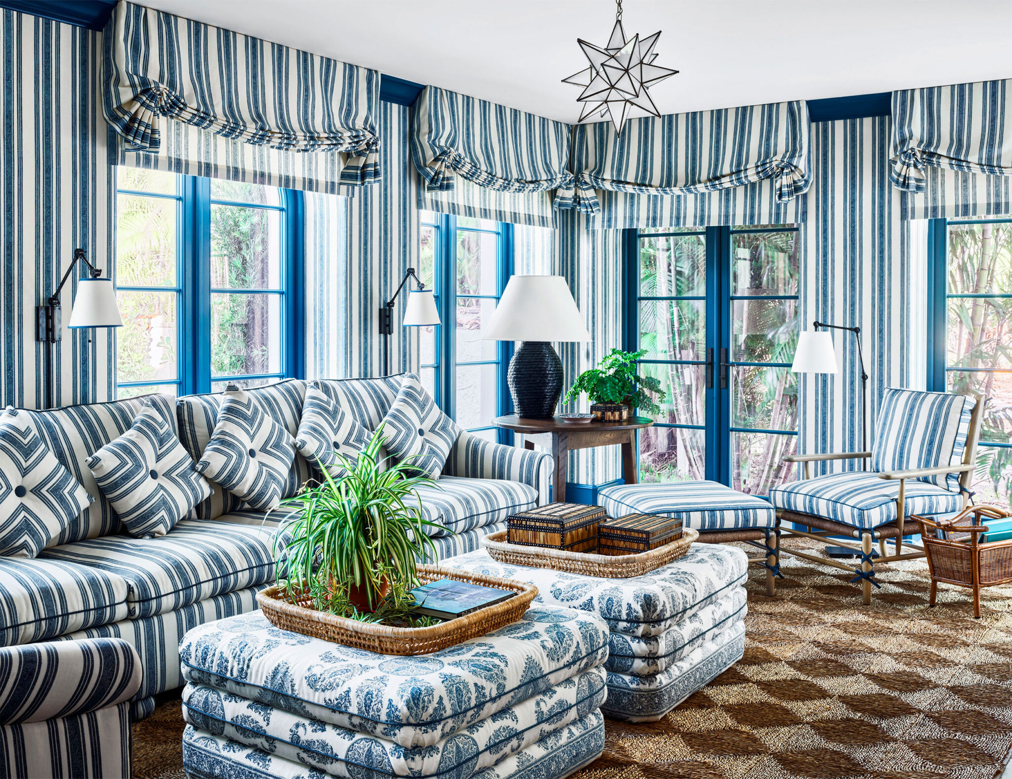 Blue and white living room with stripe wallpaper and matching fabric with a natural fiber rug