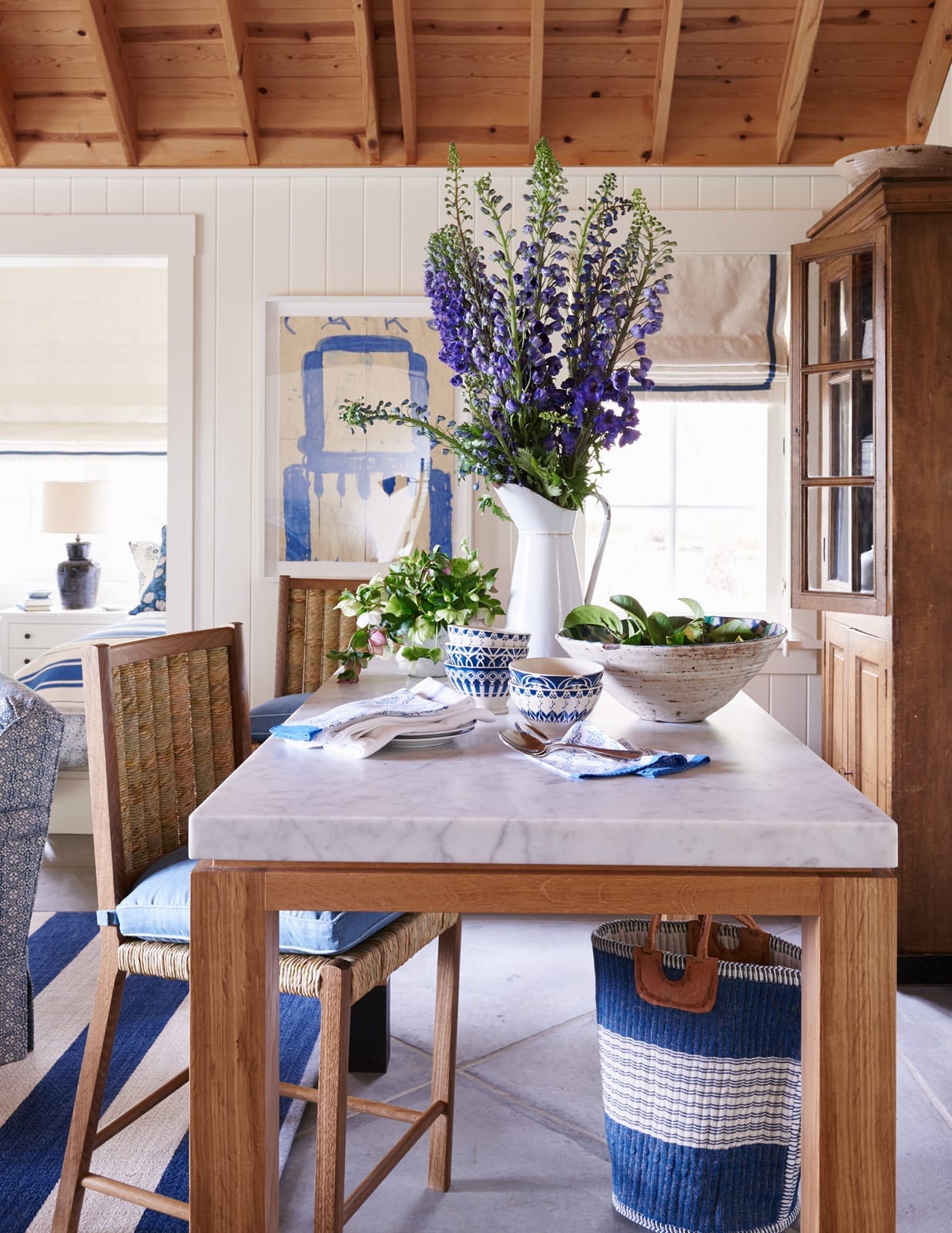 Charming kitchen with blue and white patterned fabrics, blue and white art and a blue and white stripe rug
