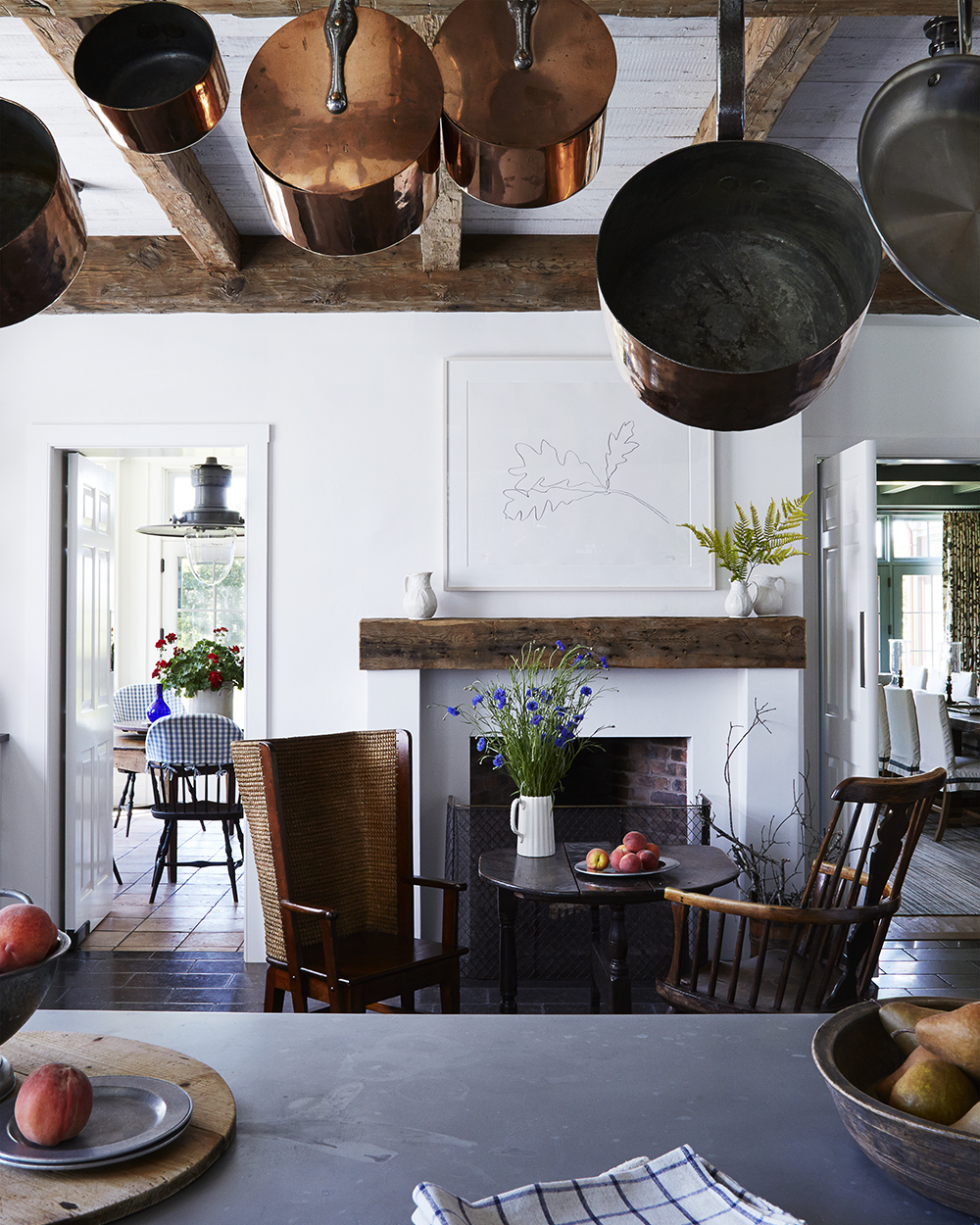 Classic white kitchen showcasing a collected home look with hanging copper pots, wood beams, and timeless traditional design