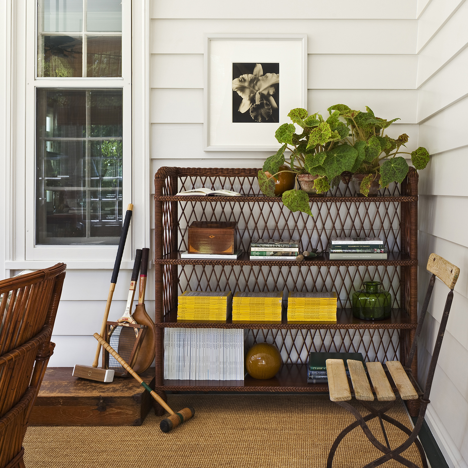 Charming porch with wicker furniture, tennis rackets, a wicker bookcase, and a traditional collected home look