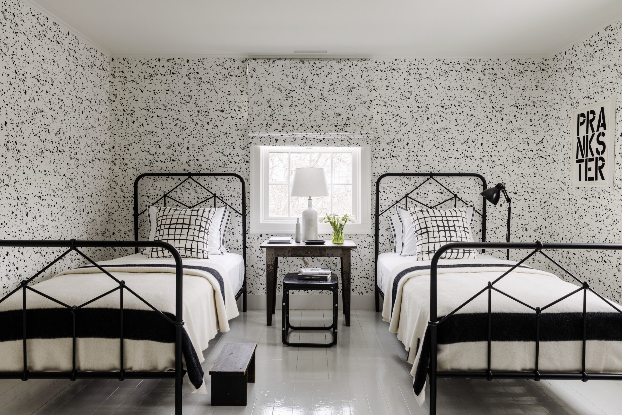 Charming twin bedroom with patterned wallpaper, black iron beds, and a classic home look