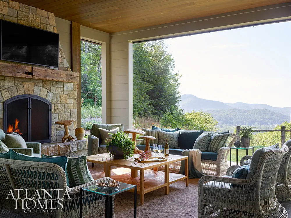 In the spirit of that, this fabulous mountain retreat is the perfect place to spend a summer day–and a great place to curl up by the fire come fall. covered porch with stone fireplace and soft seating