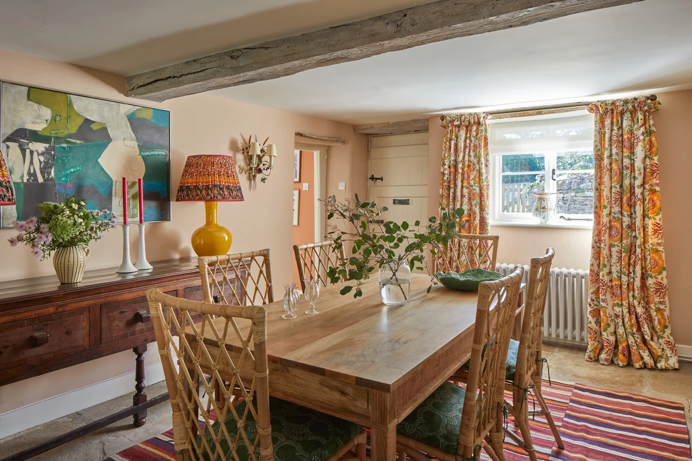 Charming Cotswold cottage dining room with patterned fabrics and abstract art