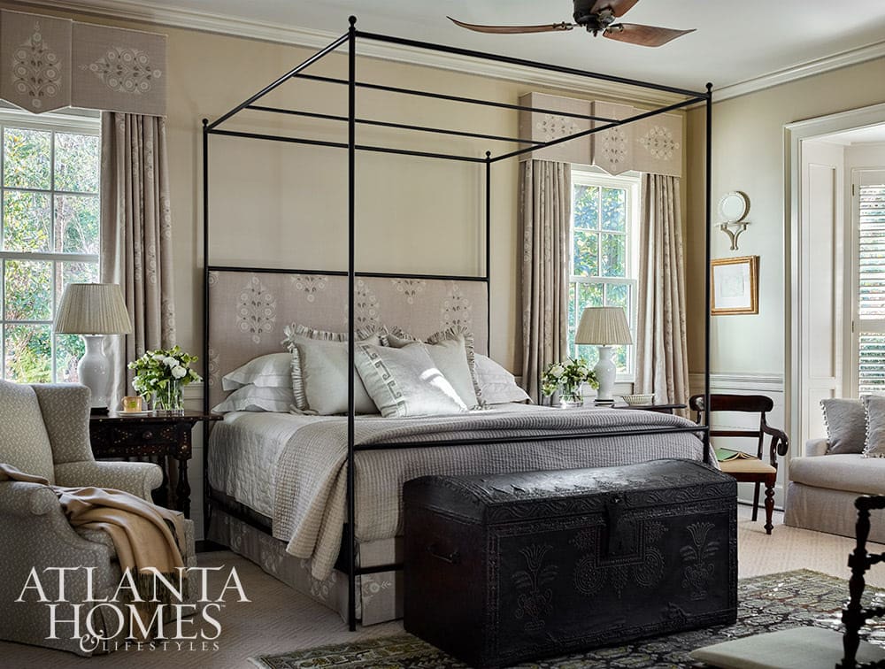 Bedroom with black canopy bed and black trunk at the foot of the bed