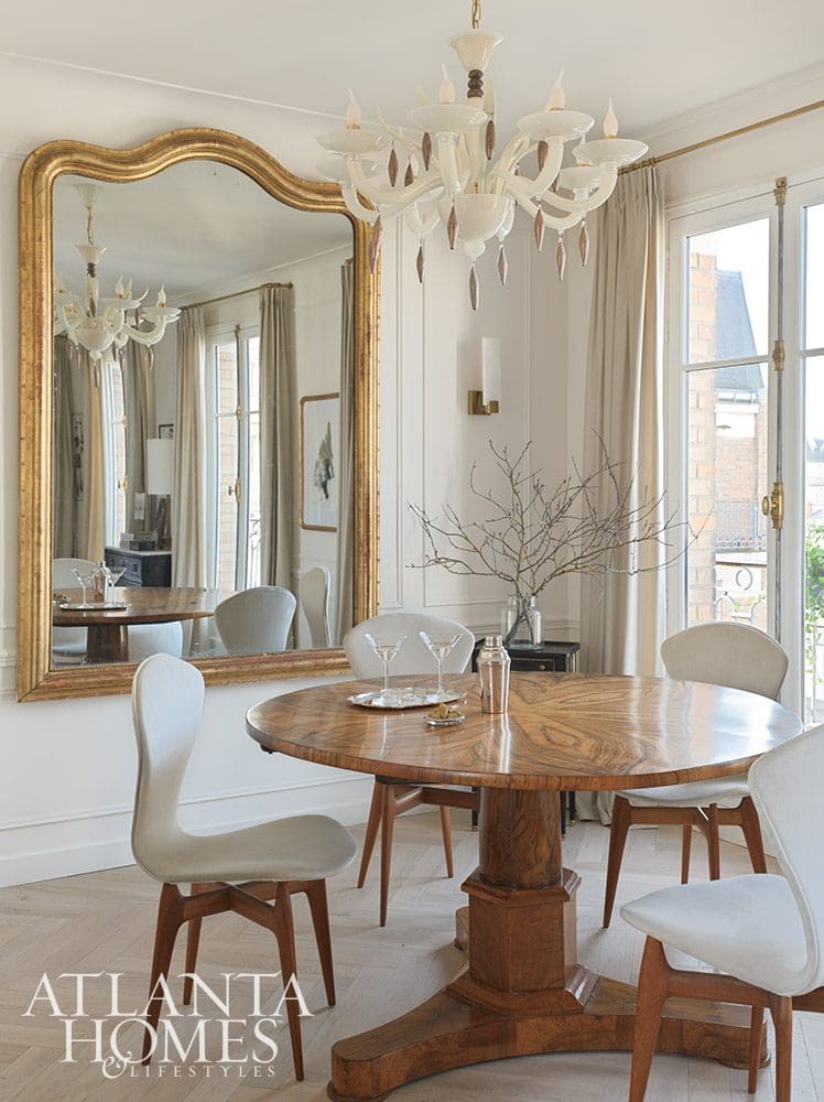 Paris is always a good idea, and when Ann Huff of Huff Harrington is designing your Paris apartment, it's an even better one! large crystal chandelier and round dining table with a large gold mirror - Source: Atlanta Homes & Lifestyles | Interior Design: Ann Huff, Huff Harrington |  Photographed by Joan Porcel