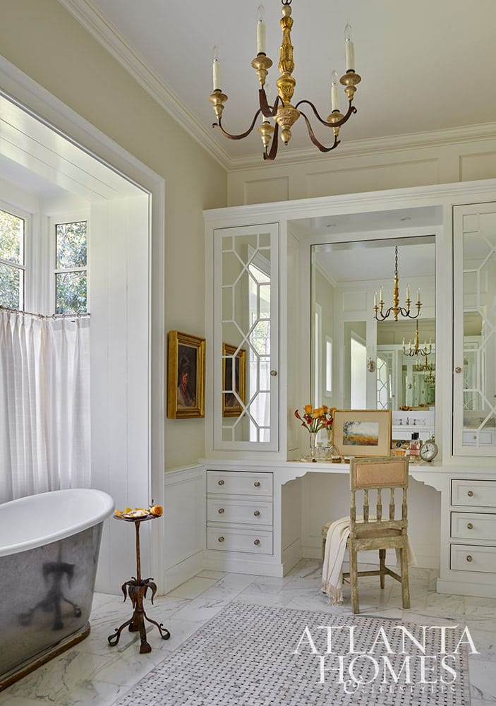 Primary bathroom with stainless steel freestanding tub and gold chandelier above