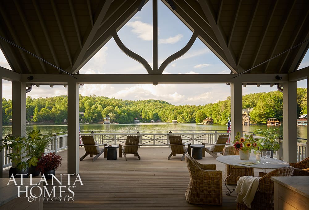Lakeside screened porch featuring traditional Adirondack chairs and a dining table overlooking the water
