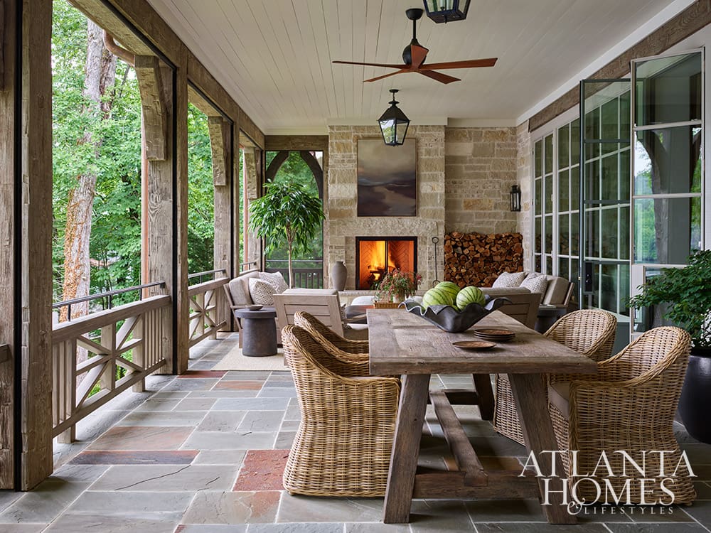 Lakeside screened porch featuring a large stone fireplace with a roaring fire and outdoor dining area