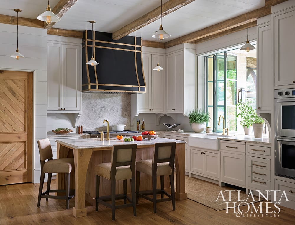 • Eclectic furniture style kitchen featuring a custom black and gold range hood and timeless classic cabinetry, and beautiful wood beams.