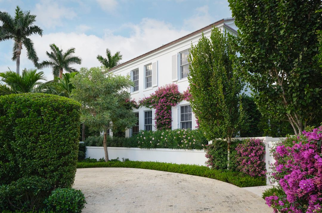 White Palm Beach home with white shutters and bougainvillea vines and palm trees - Caitlin Kah Interior Design | Brantley Photography