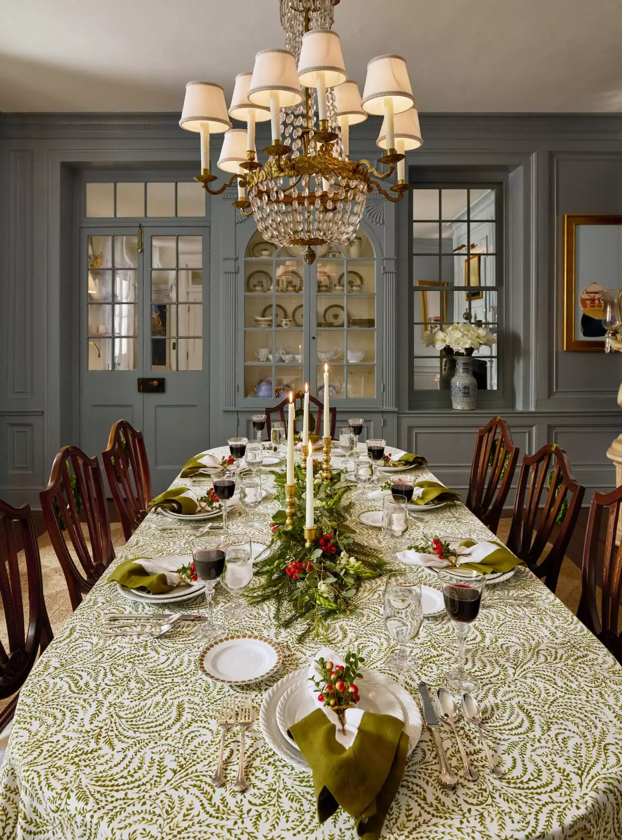 Beautiful dining table with green and white tablecloth that is decorated for the holidays. Love the fresh greenery surrounding the candles