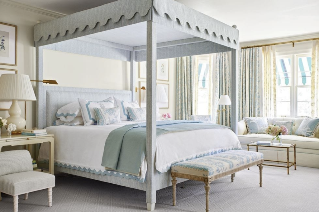 A beautiful guest bedroom with a canopy bed styled in blue and white with white lamps and cozy sofa perfect for holiday guests.