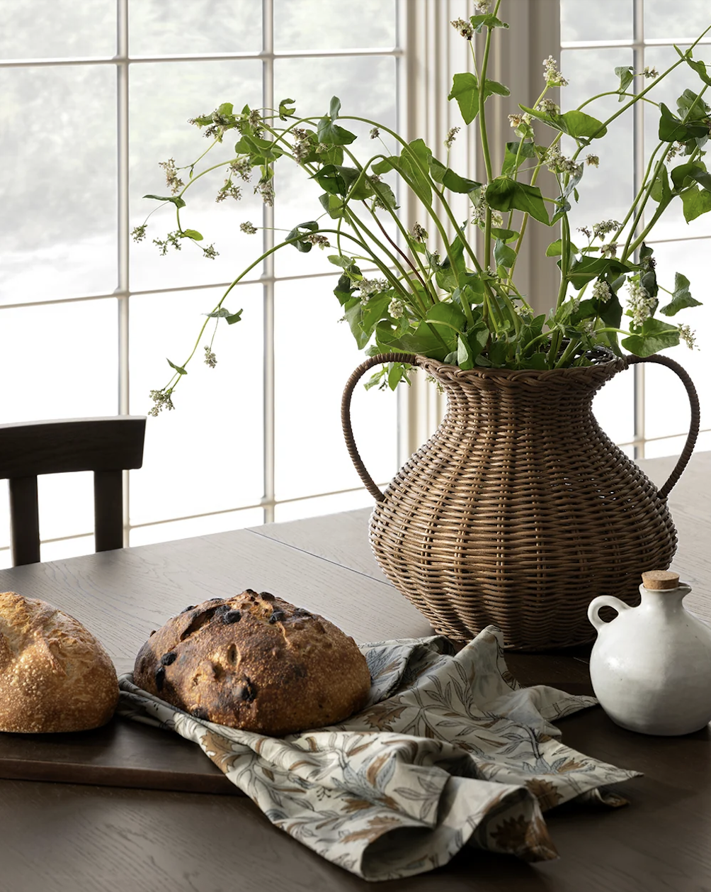 McGee & Co Antonia Woven Vase utilized as an organic wicker centerpiece on a modern dining room table layout.