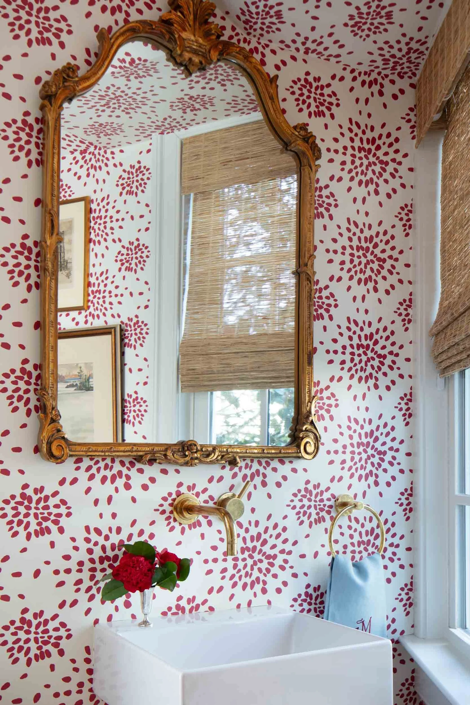 Preppy bathroom design featuring the graphic Scalamandré Color Pop wallpaper by Albert Hadley paired with brass hardware and natural bamboo window shades.