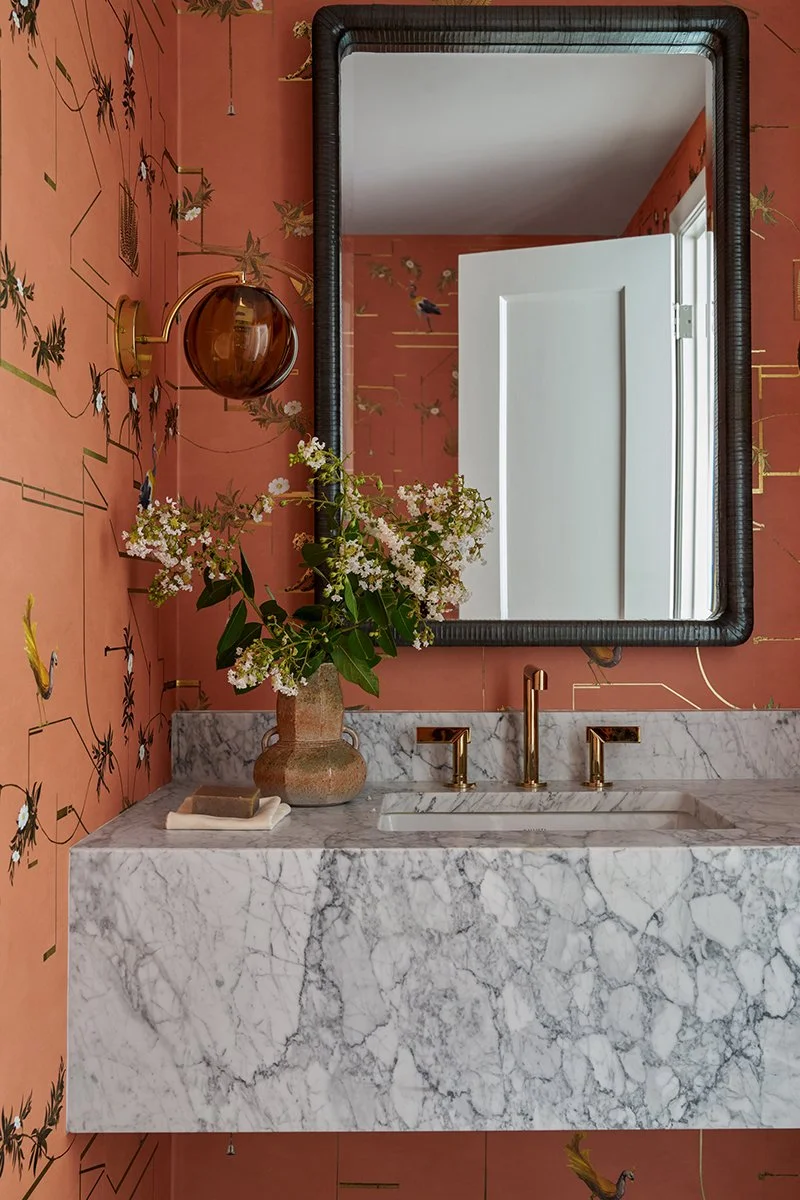 Cozy bathroom space wrapped in a warm cinnamon and paprika toned patterned wallpaper designed by Mary Beth Wagner.