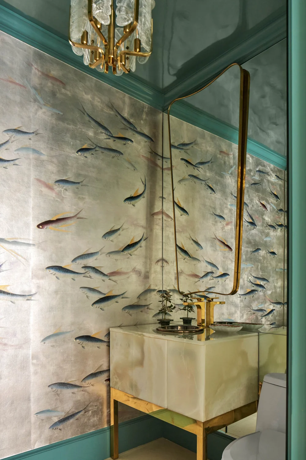Opulent jewel box bathroom clad in reflective de Gournay Amber on Real Silver Gilded Silk wallpaper accented by a dramatic black onyx vanity.