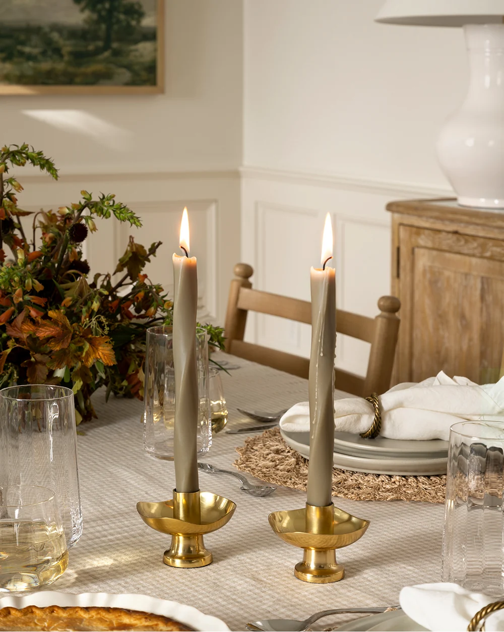 A beautiful Thanksgiving tablescape featuring green taper candles in brass holders inspired by the home of Shea McGee, adding height and ambient light to the holiday setting.